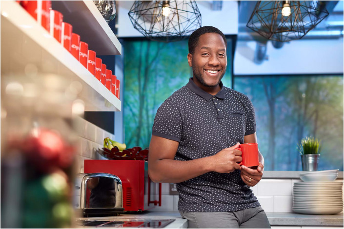black man leaning against counter top holding cup of tea