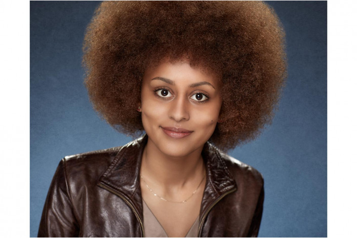 lady with afro in studio headshot against blue backdrop