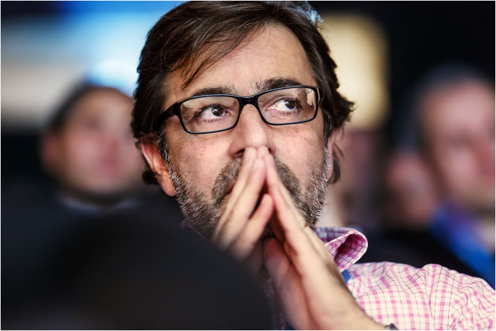 man thinking hard in audience at a conference